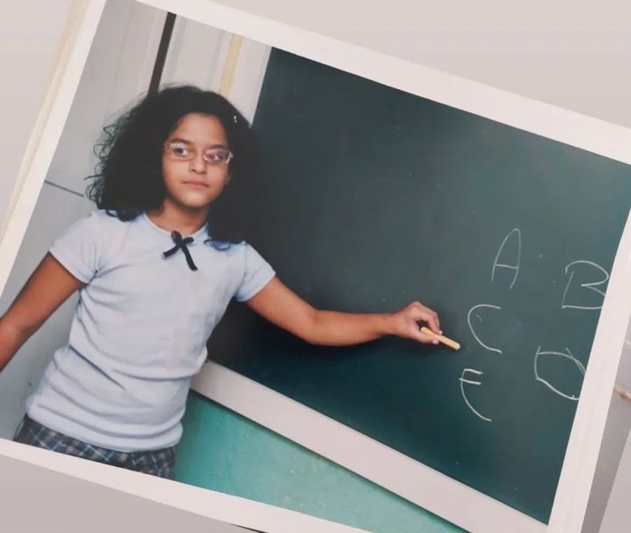Beatriz as a child writing the alphabet on a chalkboard